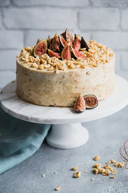 hazelnut and fig cake on a cake stand with a white background