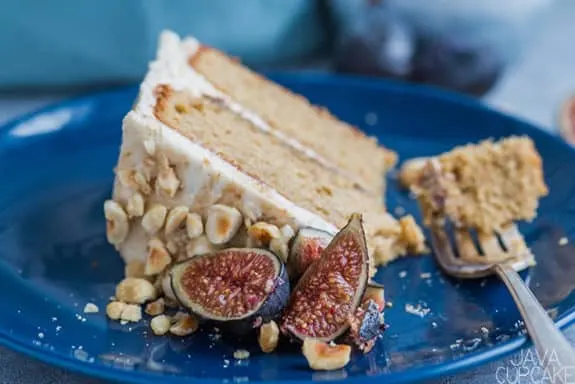 slice of hazelnut and fig cake on a blue plate with fresh sliced fig and chopped hazelnuts
