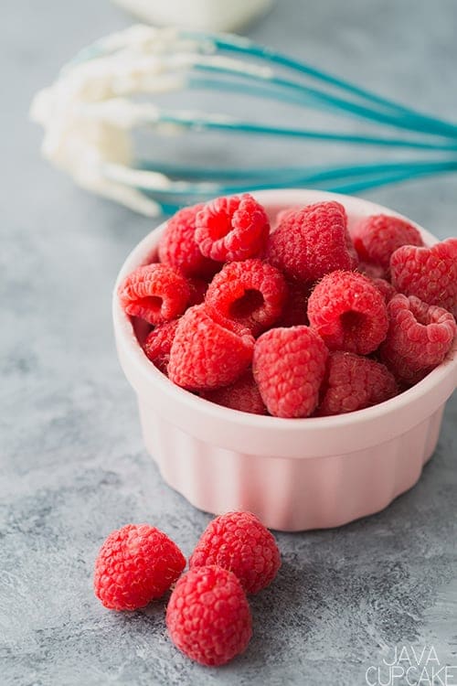 pink bowl of fresh raspberries on a counter