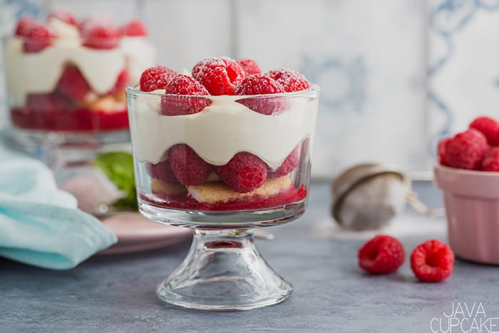 glass bowl of raspberries, biscuits, and cream on a counter