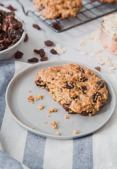 peanut butter oatmeal cookie on a plate in a kitchen with a bowl of raisins