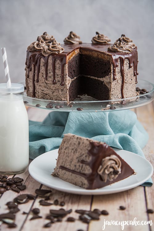 mocha cookies and cream cake on a stand with a slice of cake and a glass of milk 