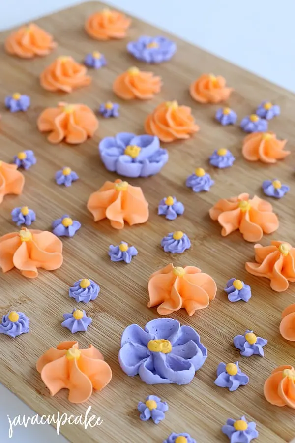Close-up image of orange and purple Royal Icing Flowers, placed on a wooden table.