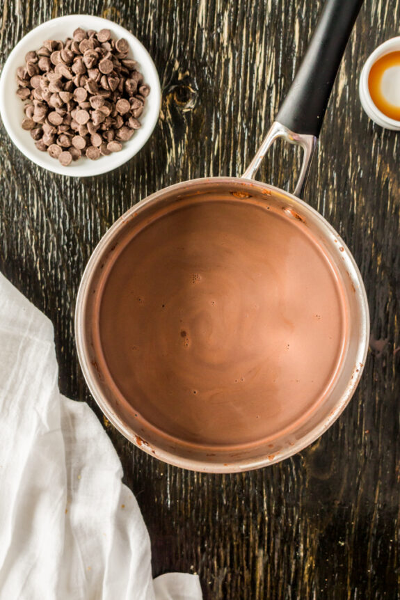 homemade hot chocolate in a pot on a counter with chocolate chips