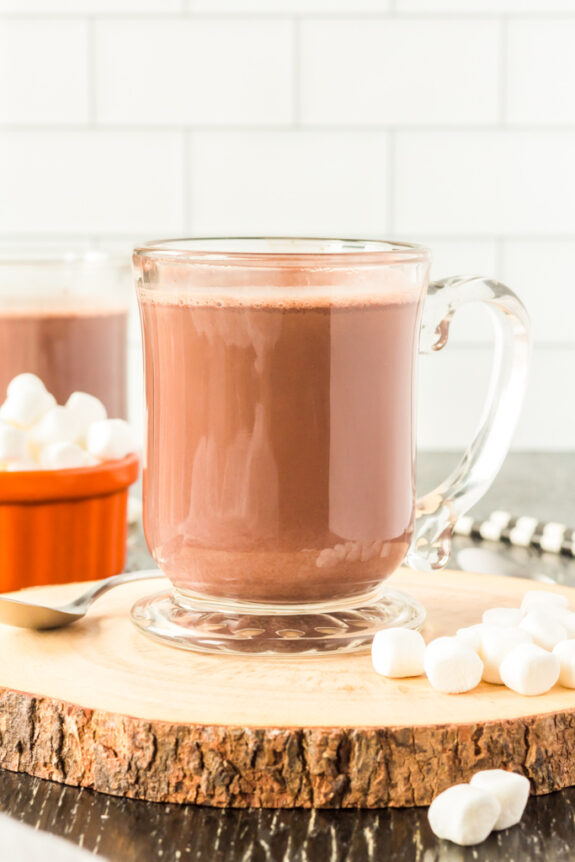 homemade hot chocolate in a glass mug on a counter with marshmallows