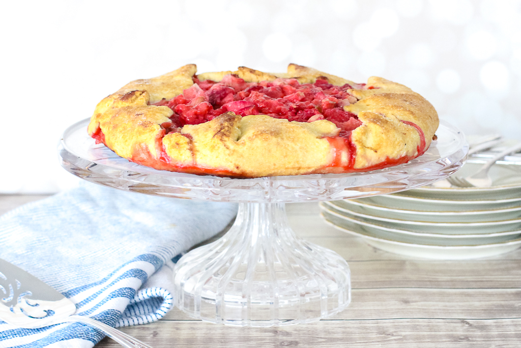 bright red berry tart sits on top of a crystal cake plate
