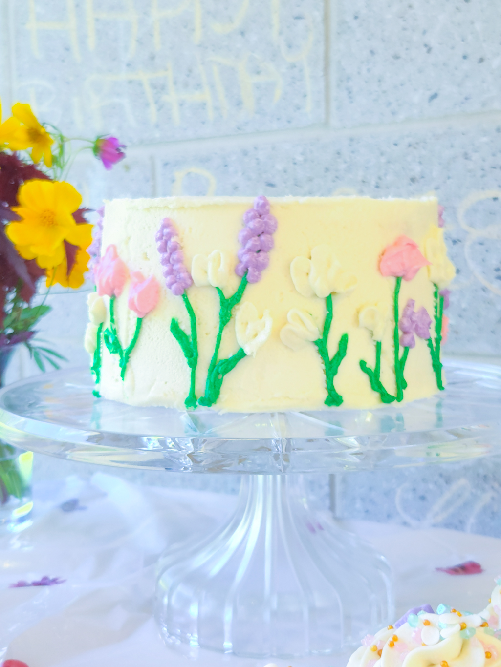 Wildflower smash cake set against a backdrop of real wildflowers and birthday decorations.