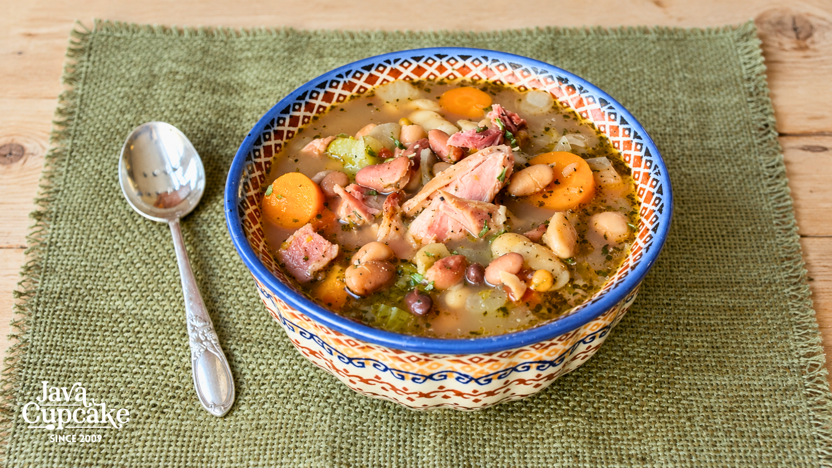 Ham hock 15 bean soup with carrots and celery in a blue-rimmed Polish pottery bowl.